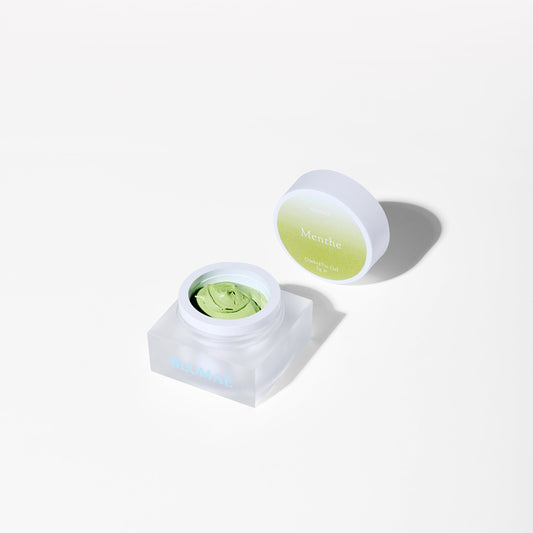 Cosmetic container with a green substance on a white background